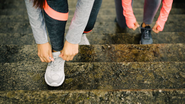 Two people tying their shoes on some steps after seeing an arthritis care specialist.
