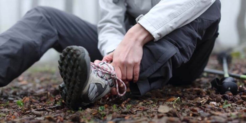 Person holding their ankle, appearing to experience pain or discomfort.