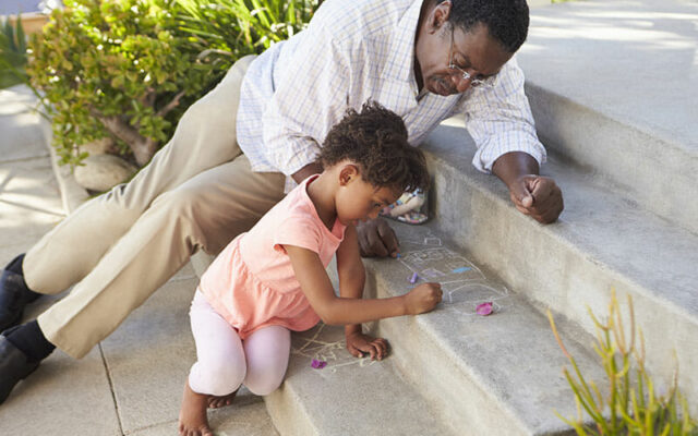 A man playing with a little girl on some concrete steps after seeing a hip care specialist 